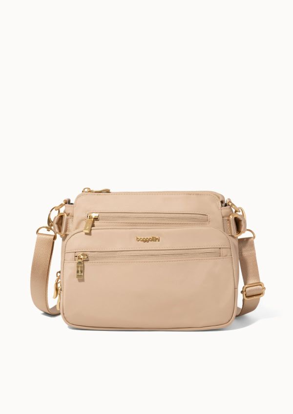 Front view of a beige crossbody bag featuring multiple zippered compartments and gold-tone hardware.