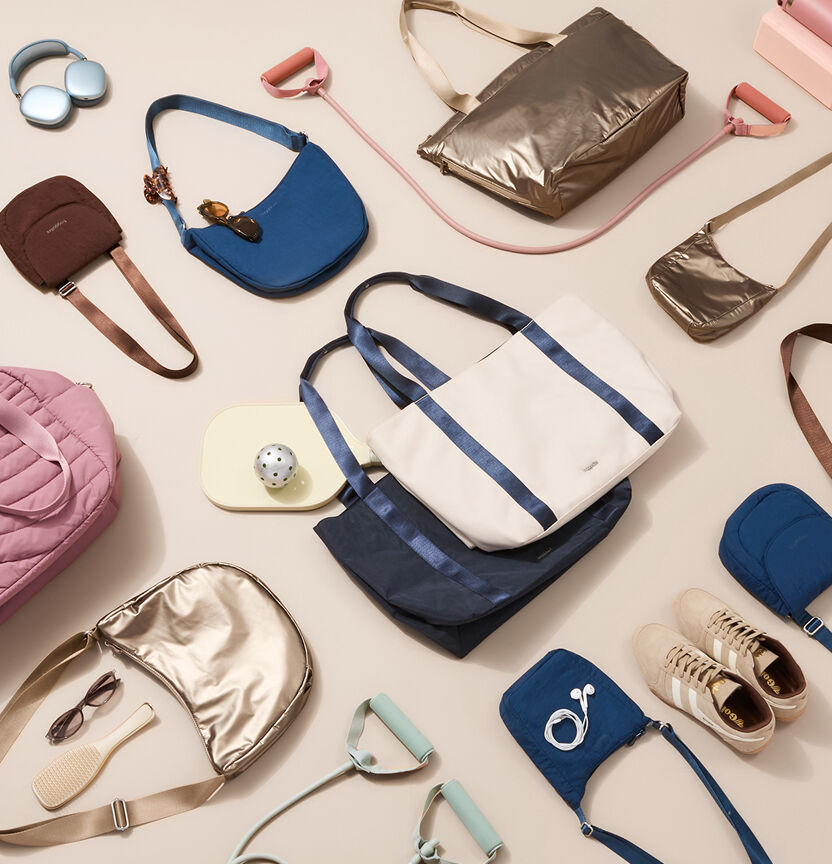 Assortment of Baggallini totes, crossbody bags, and accessories in blue, pink, metallic, cream, and brown arranged with headphones, sneakers, sunglasses, and other everyday essentials.