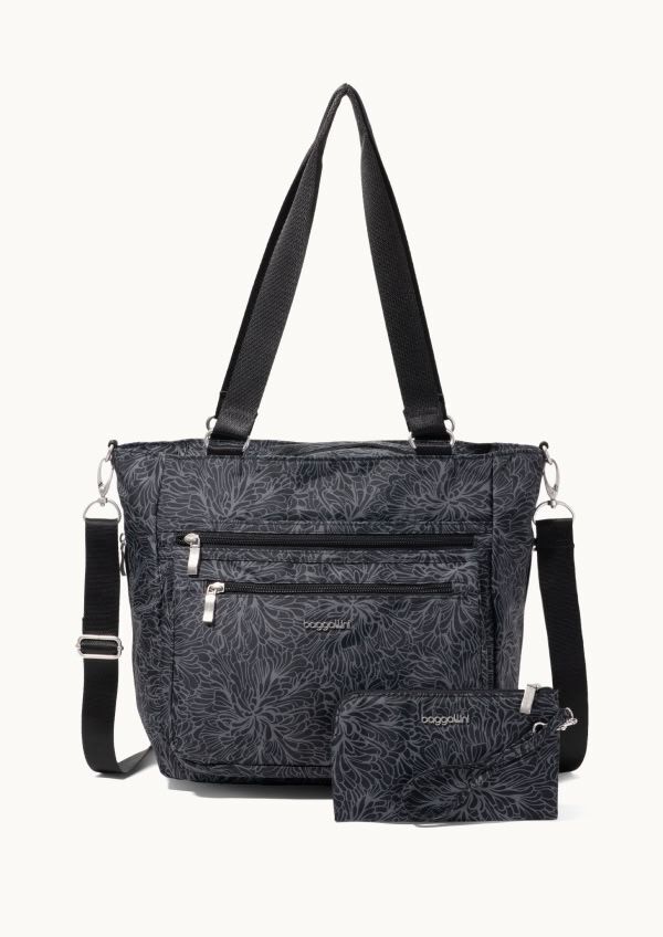 Black floral-print tote bag with front zip pockets, double shoulder straps, and matching pouch displayed on a neutral background.