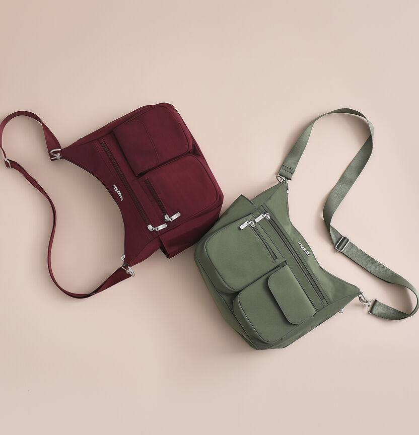 Burgundy and olive green Baggallini sling bags with multiple zippered pockets and adjustable straps arranged on a neutral background.