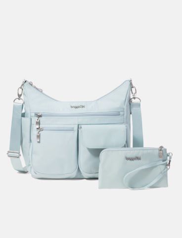 A light gray crossbody bag with multiple zippered pockets is displayed alongside a matching wristlet pouch.
