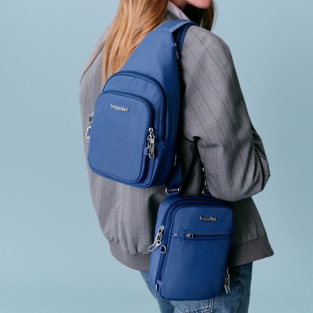 A woman wearing a gray jacket models two blue, securtex crossbody bags, one worn on the back and the other on the side, against a plain light blue background.